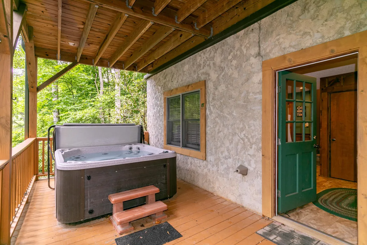 This image features a tranquil outdoor hot tub set on a wooden deck surrounded by greenery, offering a relaxing space immersed in nature. The hot tub is positioned to maximize views of the surrounding woods, creating an inviting spot for unwinding after a day of adventure.