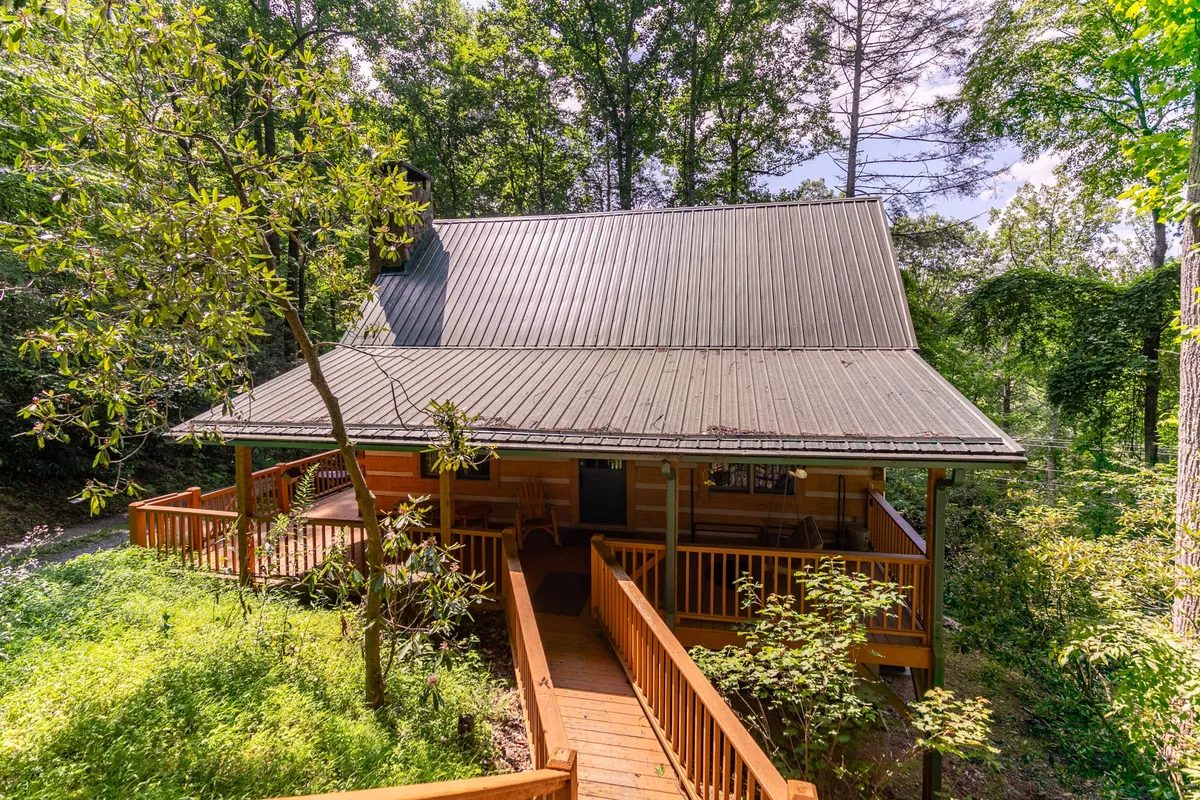 A peaceful wooden deck surrounded by lush trees, with inviting seating—ideal for sipping morning coffee or unwinding to the sounds of nature. The deck feels seamlessly accessible from the main living spaces, providing an extension of the cabin’s comfort into the outdoors.
